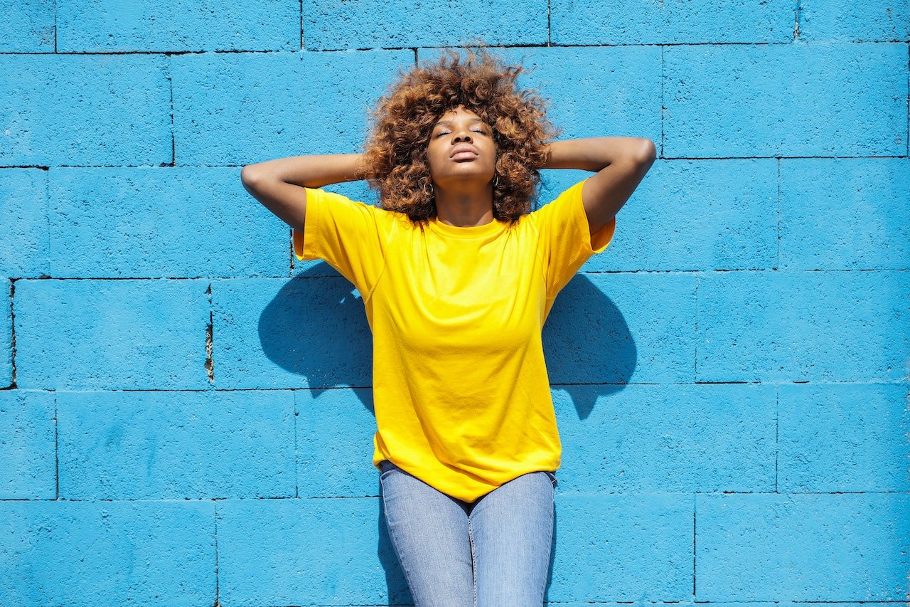 lady bathing in sunlight agaisnt wall